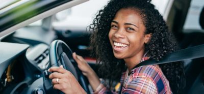 Young woman behind the steering wheel of a car as an international student
