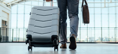 person walking with a traveling bag and a suitcase