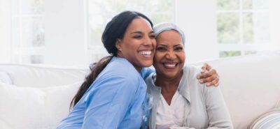 A patient smiling in home with her caregiver.